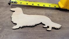 a wooden cutout of a dog next to a measuring tape on top of a table