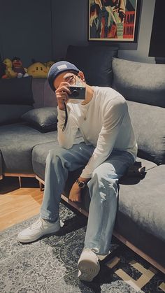 a man sitting on top of a couch holding a camera