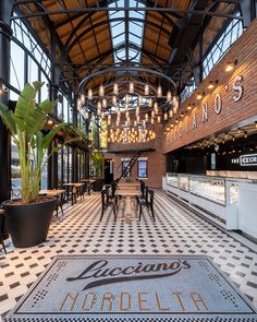 the inside of a restaurant with black and white checkered flooring, potted plants, and chandeliers