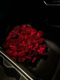 a bouquet of red roses sitting in the back seat of a car at night time