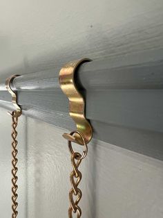 a close up of a metal hook on a wall with chains hanging from it's sides