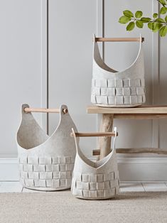 two white baskets sitting next to each other on top of a wooden table with a plant in it