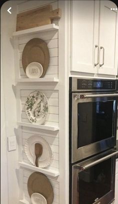 an oven and microwave in a kitchen with plates on the shelves above it, along with other appliances