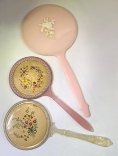 three different types of spoons and plates on a white counter top, one with flowers painted on it