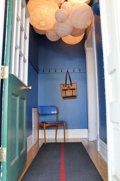 a hallway with blue walls and white ceiling lights hanging from it's ceiling above a chair