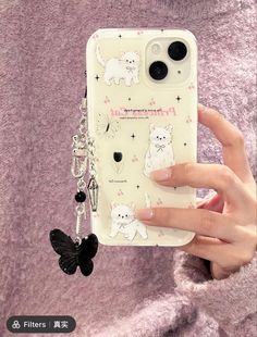 a person holding up a phone case with cats on it and a butterfly keychain