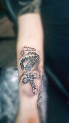 a person with a rosary tattoo on their arm