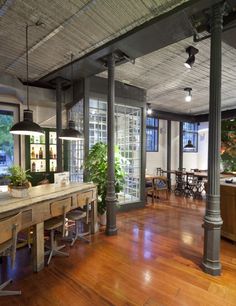 an open kitchen and dining area with wood floors, large windows, and potted plants