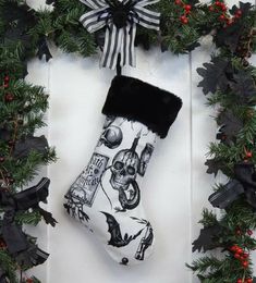 a christmas stocking hanging on a door with holly wreaths and decorations around it