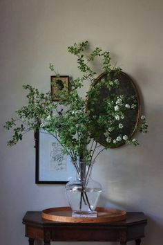 a vase filled with white flowers sitting on top of a table next to a mirror