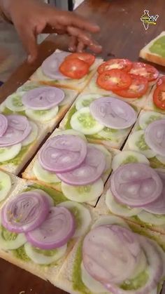 there is a sandwich with onions and tomatoes on it that has been cut into squares