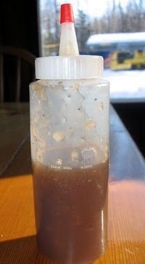 a plastic bottle filled with liquid sitting on top of a wooden table