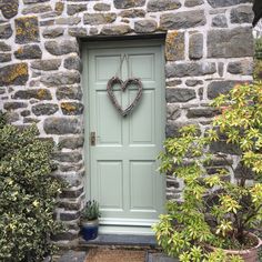 a heart shaped wreath hangs on the front door of a stone house