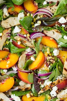 a salad with chicken, peaches, and feta cheese on top is ready to be eaten