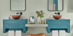 a bathroom with two sinks and three mirrors on the wall, one is blue and the other is white