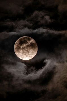 the full moon is seen through dark clouds