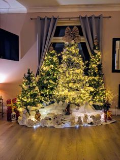 a decorated christmas tree in the corner of a room with lights on it and presents underneath