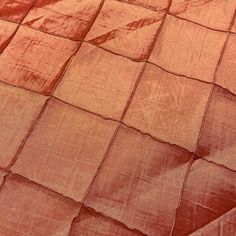 an orange blanket is laying on top of a bed sheet that has been folded over