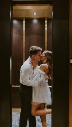 a man and woman kissing in front of a glass door at the entrance to an elevator