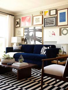 a living room with blue couches and pictures on the wall above them in various frames