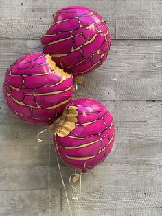 three pink balloons with gold foil designs on them