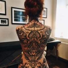 the back of a woman's body with tattoos on it