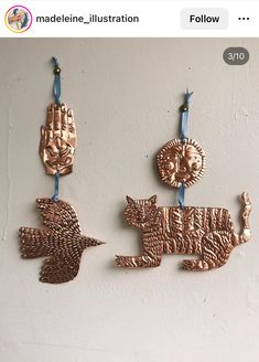 three metal ornaments hanging on a wall next to each other, one has a bird and the other is a cat