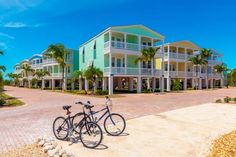 two bikes are parked in front of the multi - story building with palm trees on both sides