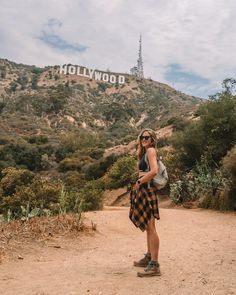 a woman standing in front of the hollywood sign