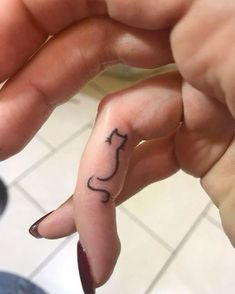 a person with a cat tattoo on their finger