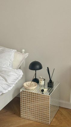 a white bed sitting next to a lamp on top of a wooden floor