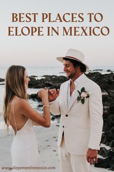 a man in a white suit and tie standing next to a woman on the beach