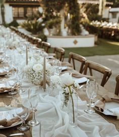 a long table is set with white flowers and place settings