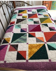 a bed with a colorful quilt on top of it