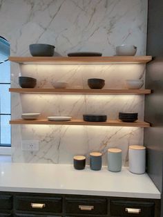 the shelves in this kitchen are lined with black and white bowls, cups, and saucers