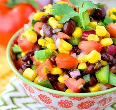 a bowl filled with black beans, corn and cilantros on top of a table