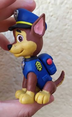 a small toy dog in a police uniform is being held by someone's hand