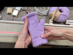 a person is holding a purple mitt in front of some knitting machines and yarn