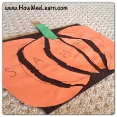 an orange pumpkin cut out on the ground with a green piece of paper sticking out of it