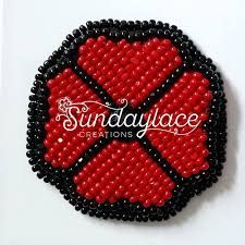 a red and black beaded brooch with the words sundialce creations on it