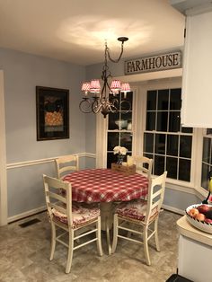 a dining room table and chairs with a red checkered tablecloth on it in front of a window