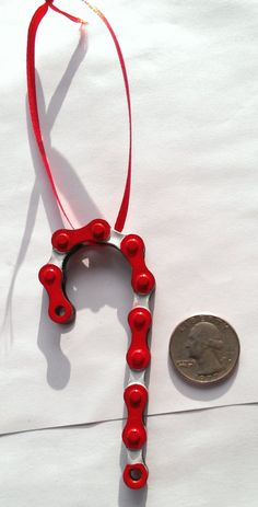 a penny is sitting next to a red necklace on a white surface with the word love spelled in small letters