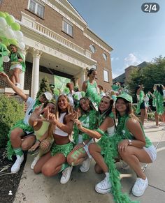 a group of young women in green outfits posing for a photo with balloons and cheerleaders