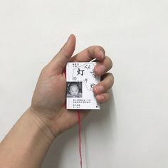 a hand holding a piece of paper with writing on it and string attached to it