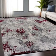 a living room with a white couch and red rugs on the floor in front of a window