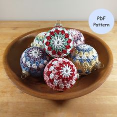 four crocheted ornaments in a bowl on a wooden table with the text free pattern below