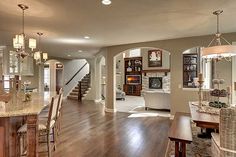 a large open concept living and dining room area with hardwood floors, wood flooring and white walls