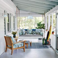 the porch is decorated with blue and green pillows, chairs, and rugs on it