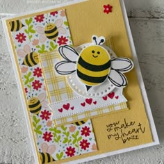 a close up of a card with a bee on it and flowers in the background