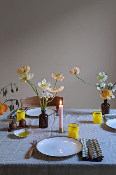 the table is set with plates and flowers in vases, candlesticks and napkins